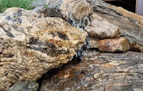 Large tan and gray boulders with a small stream of water trickling through them.