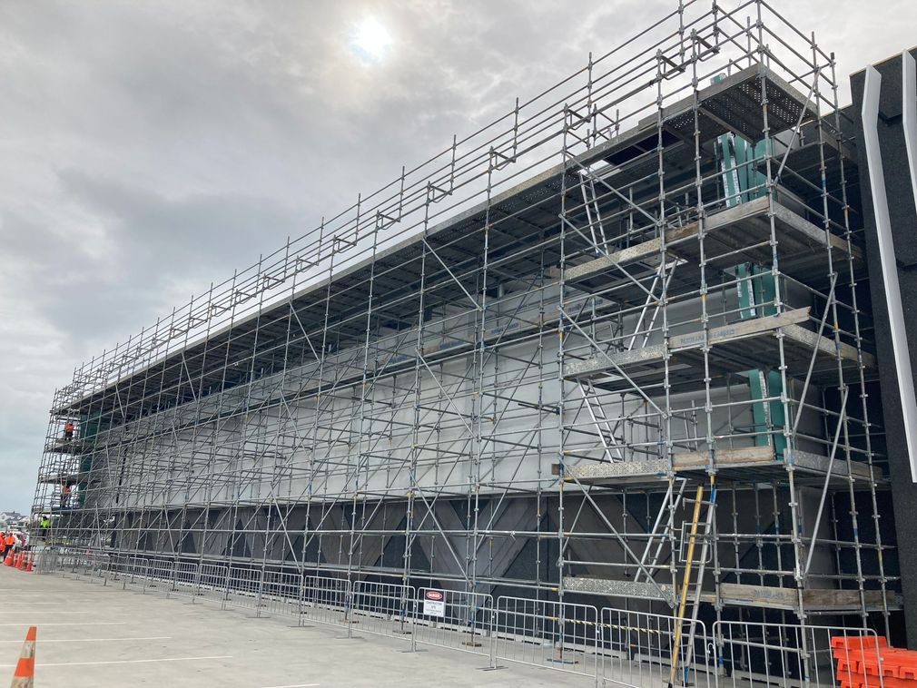 Scaffolding around a long building under construction on a cloudy day