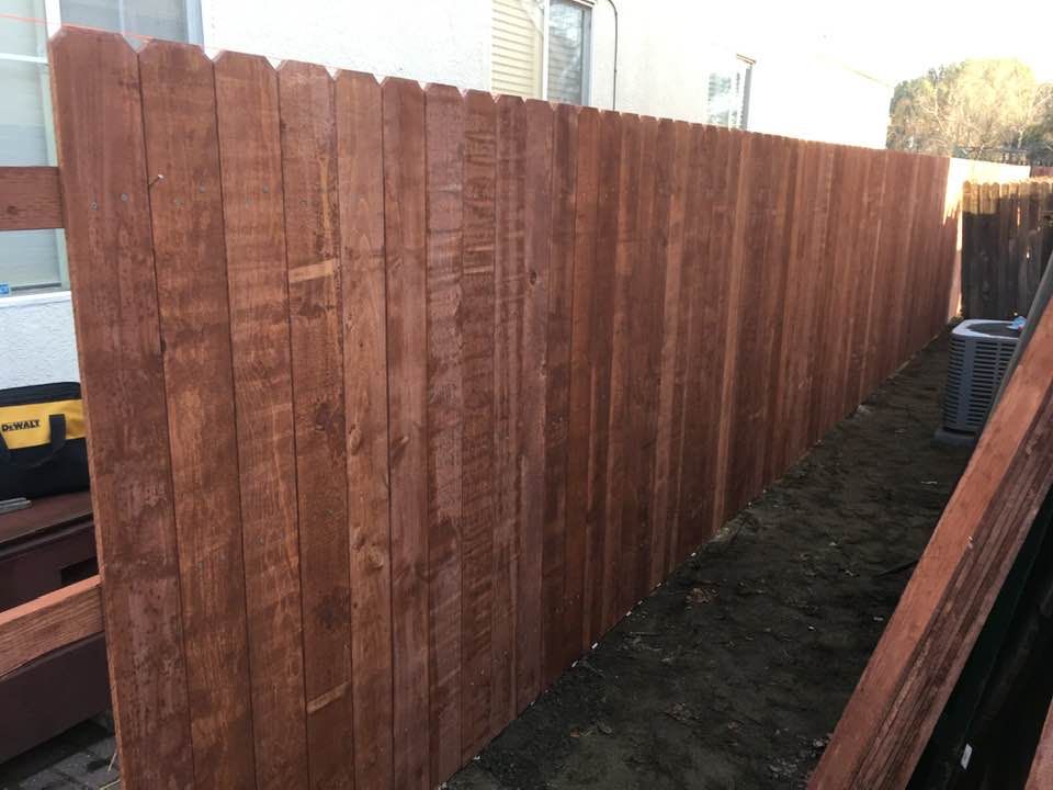 Brown wooden fence in a yard, newly built, with posts.