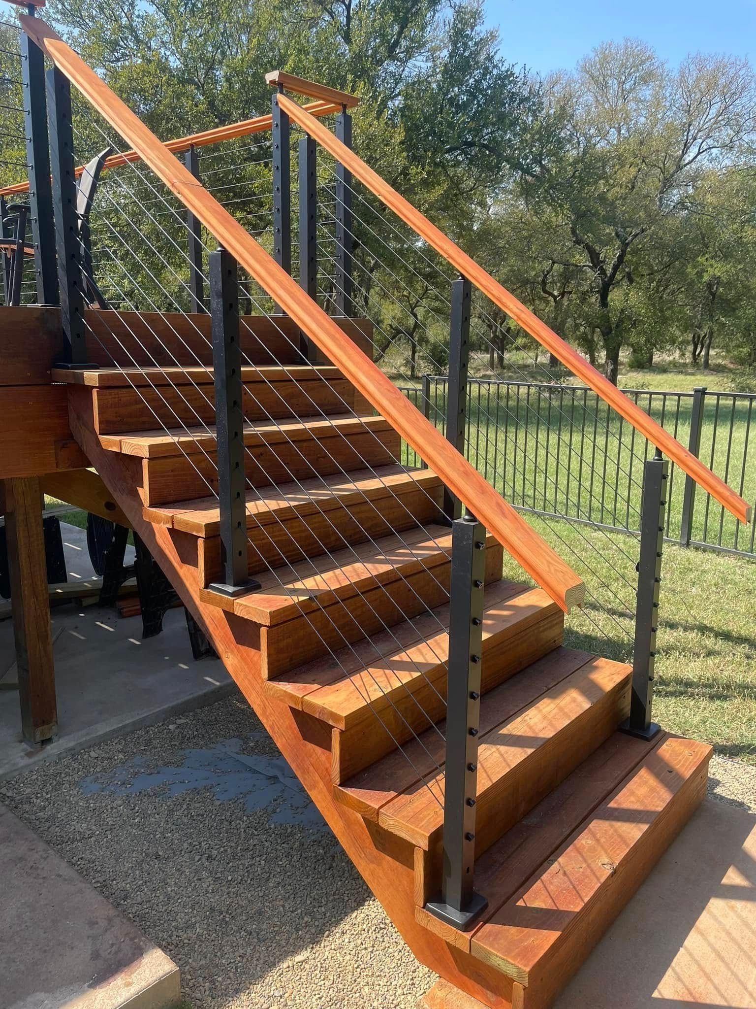 Wooden outdoor staircase with black metal railings and wooden handrails, leading to a deck.