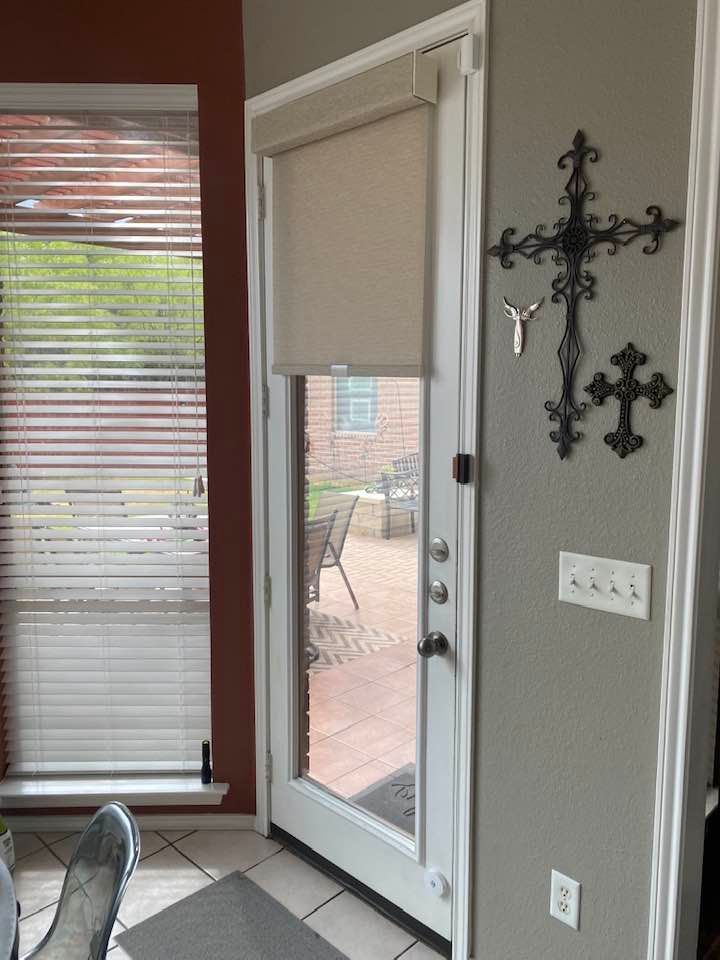 Door with a beige shade, small window to the left, and decorative crosses on the wall.
