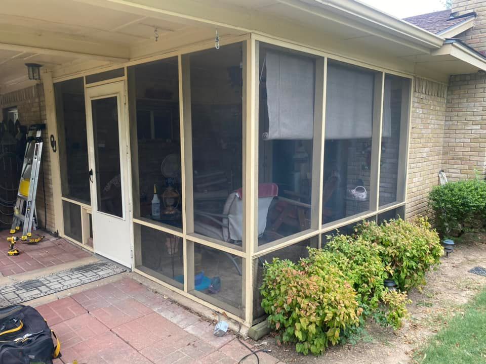 Screened porch with beige frames and door, brick patio, and landscaping.