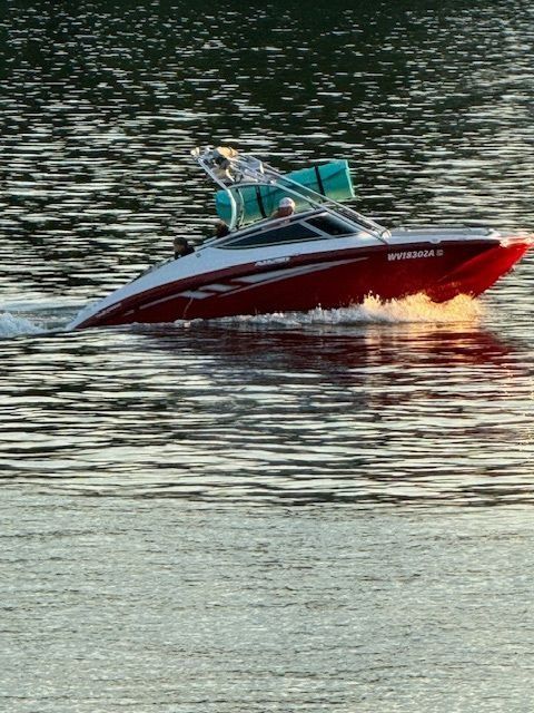 Red speedboat gliding across rippling water at sunset