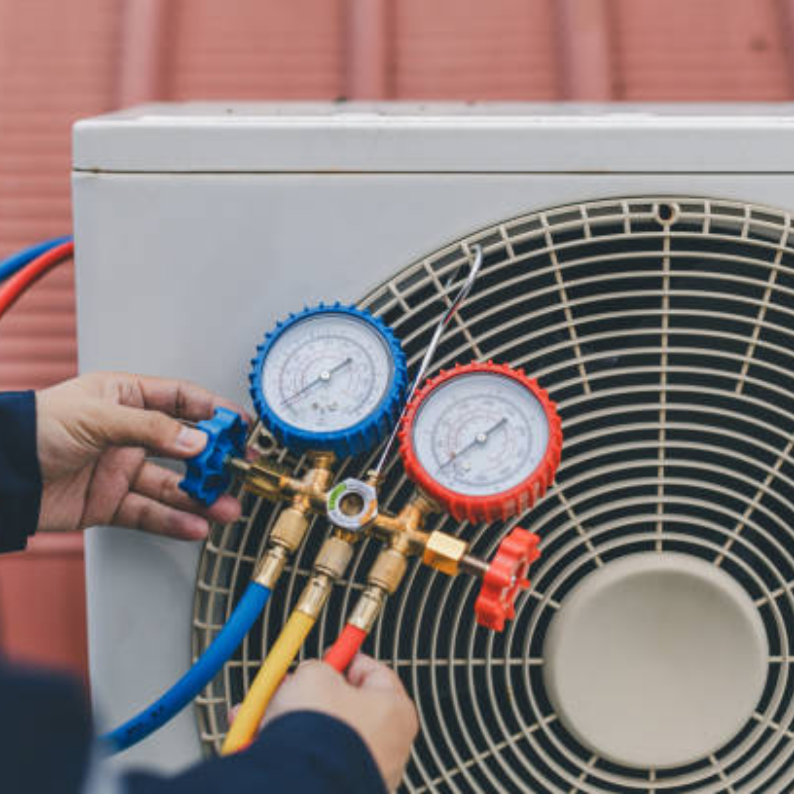 Technician connecting gauges to an outdoor air conditioner unit for HVAC service