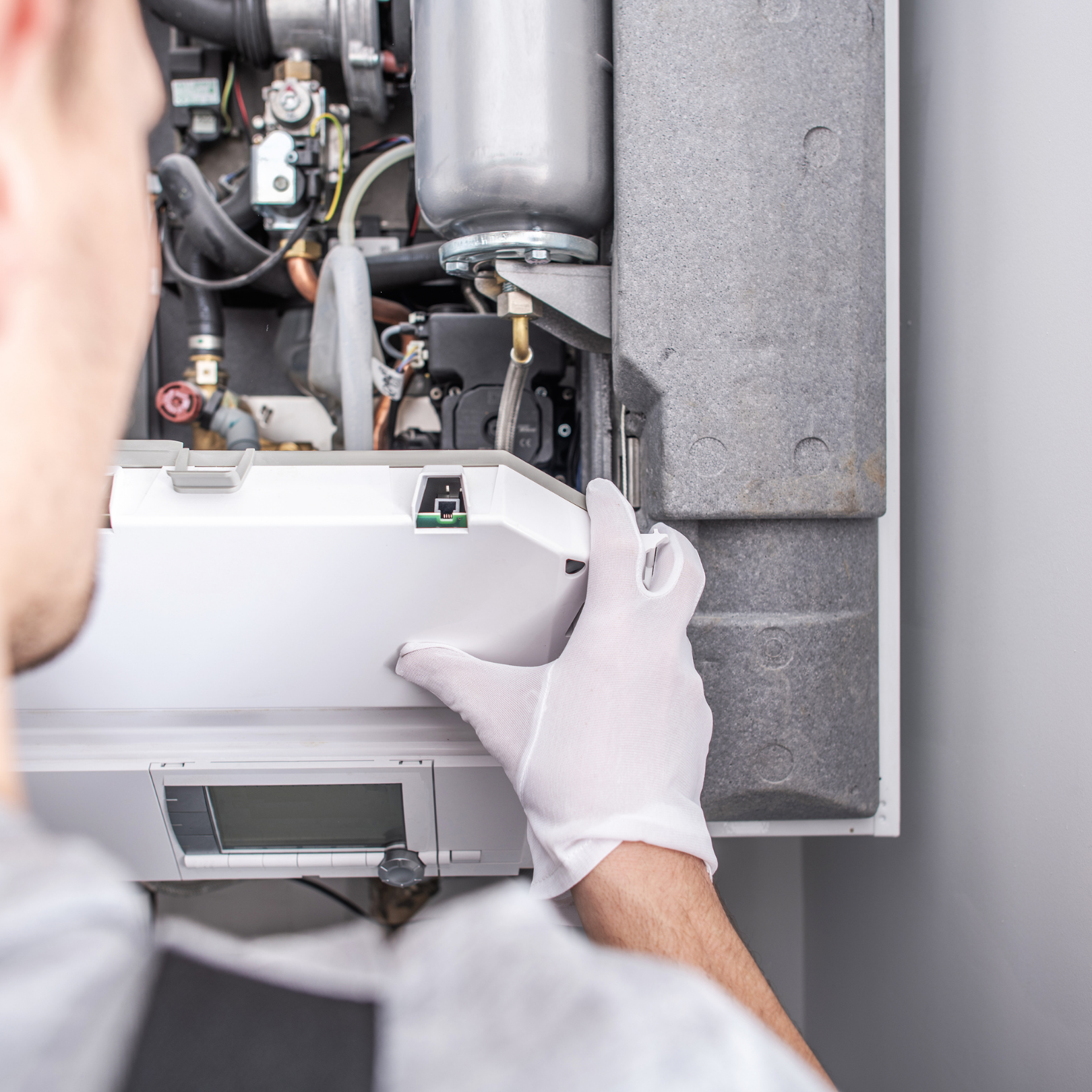 Technician installing an indoor HVAC unit with gloved hands beside exposed components
