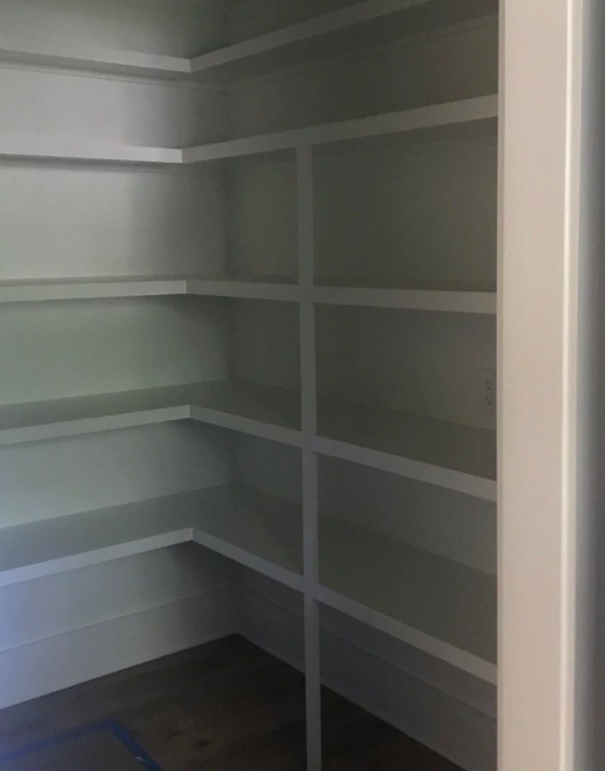 A closet with a lot of shelves and a door.
