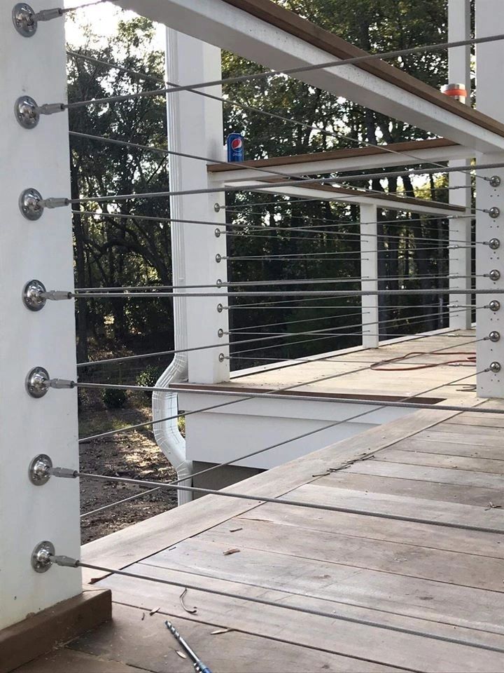 A wooden deck with a stainless steel railing and trees in the background