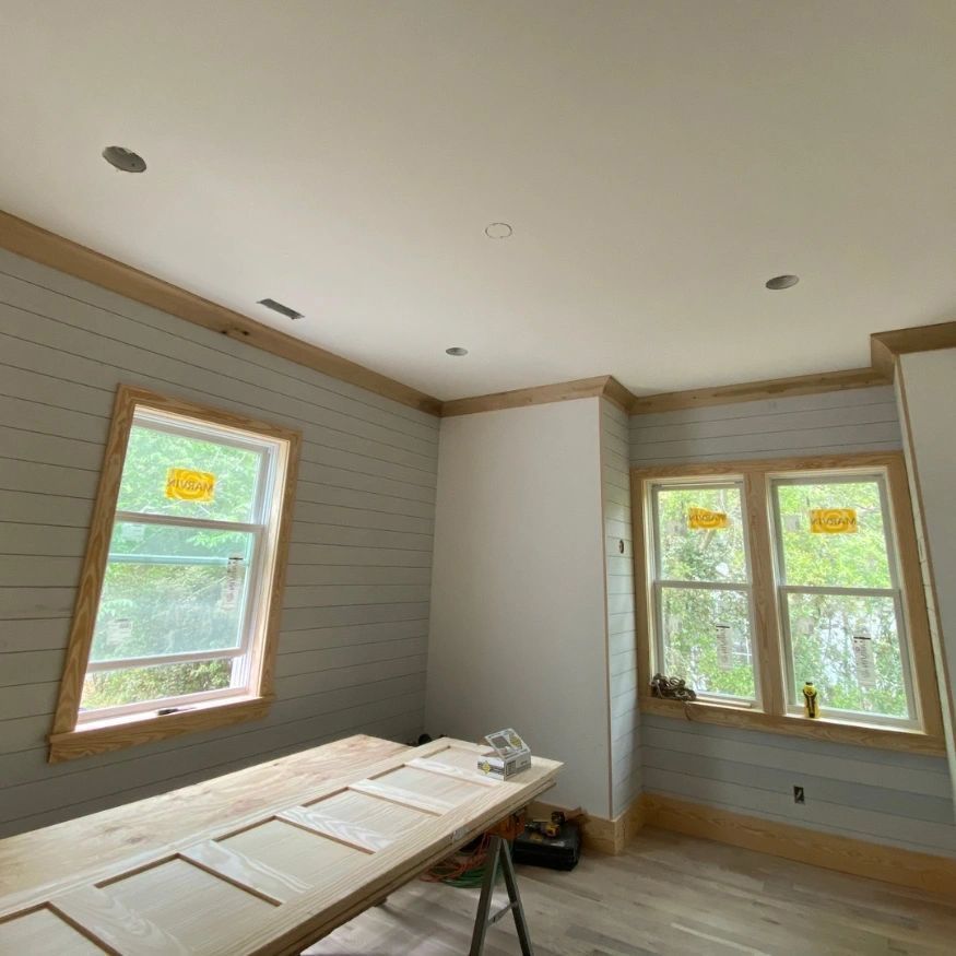 A room with a wooden table and lots of windows.