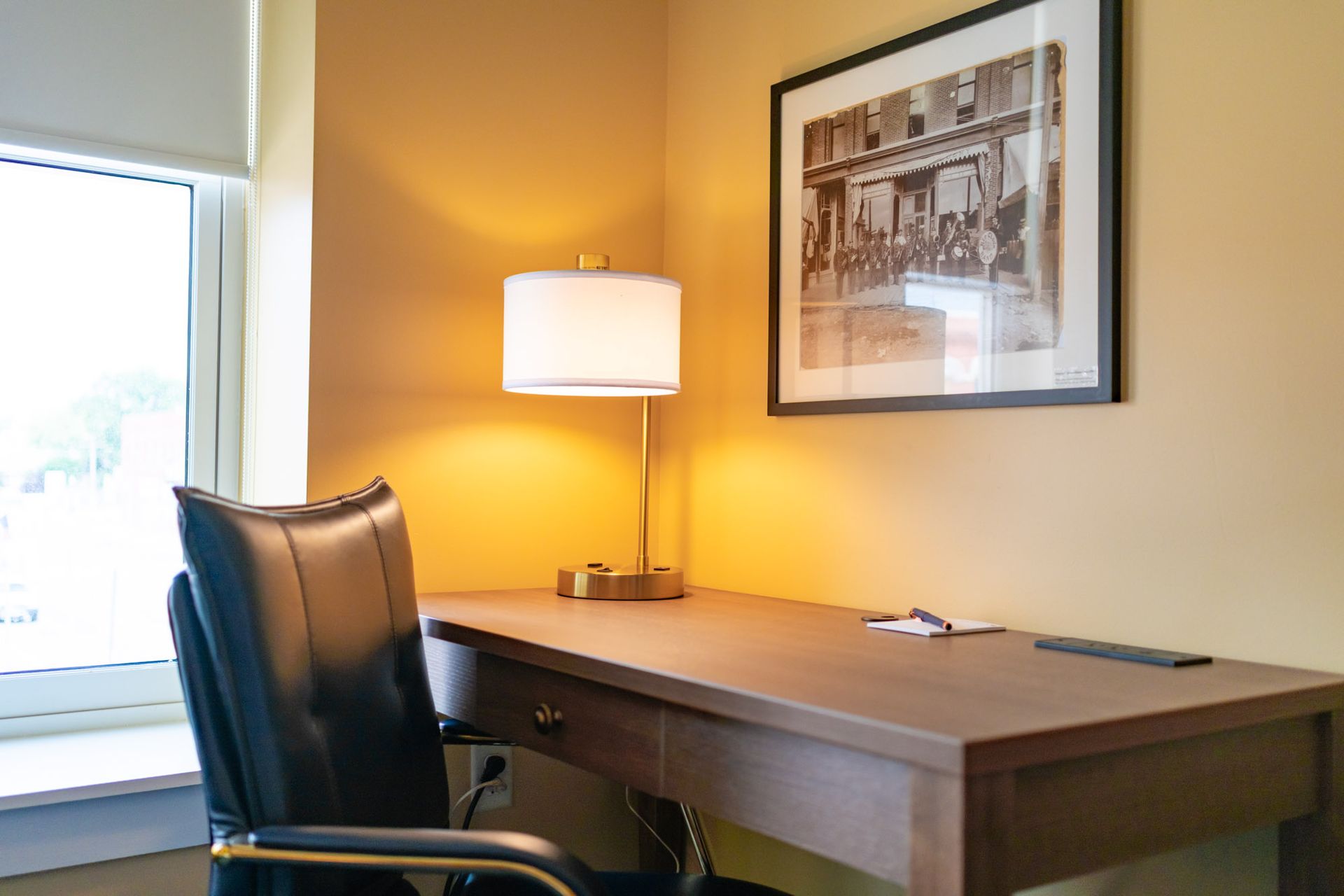 A hotel room with a work desk and lounge chair.