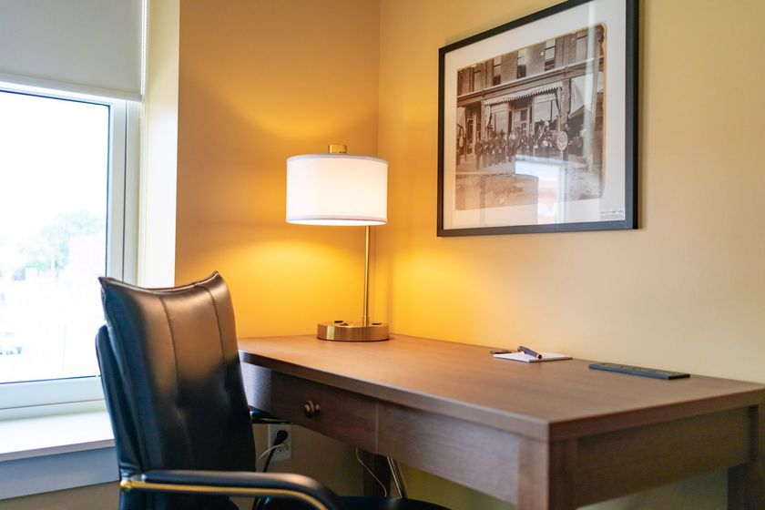 A hotel room with two beds , a desk , a chair and a flat screen tv.
