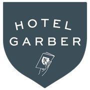 A logo for hotel garber with a hand holding a notebook