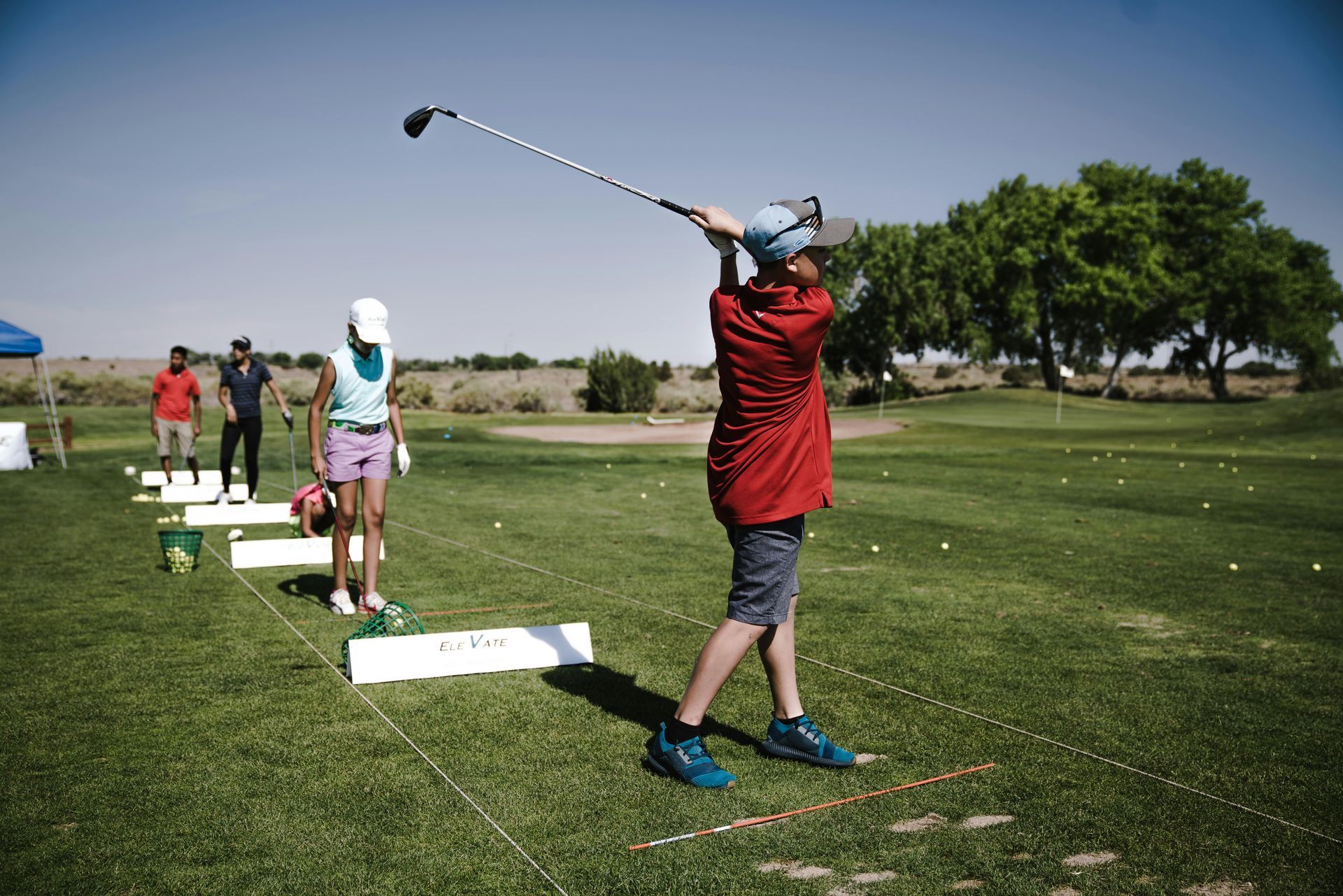 A man is swinging a golf club at a golf ball on a golf course.