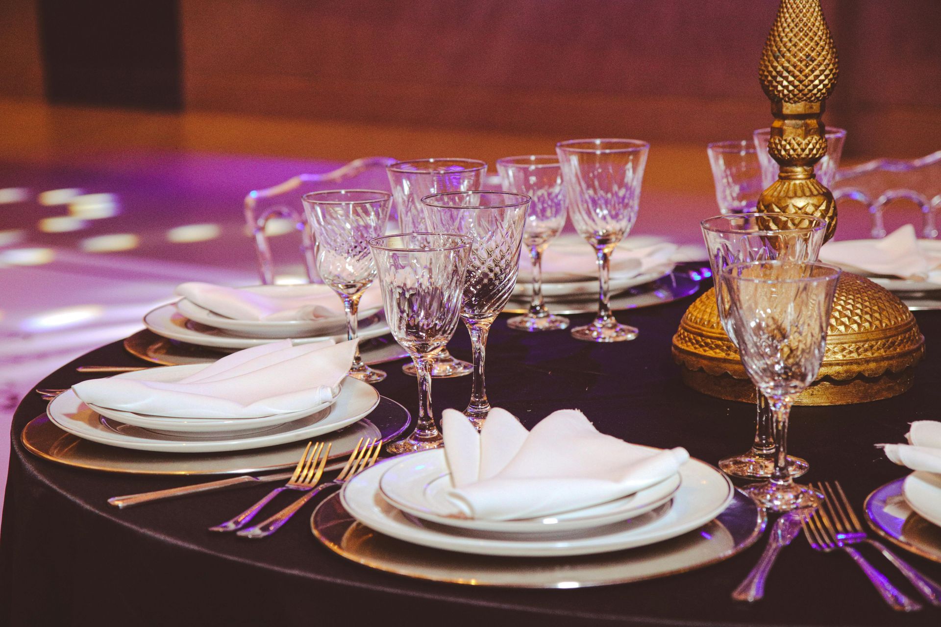 Elegant table setting with white plates, crystal glasses, and gold accents.