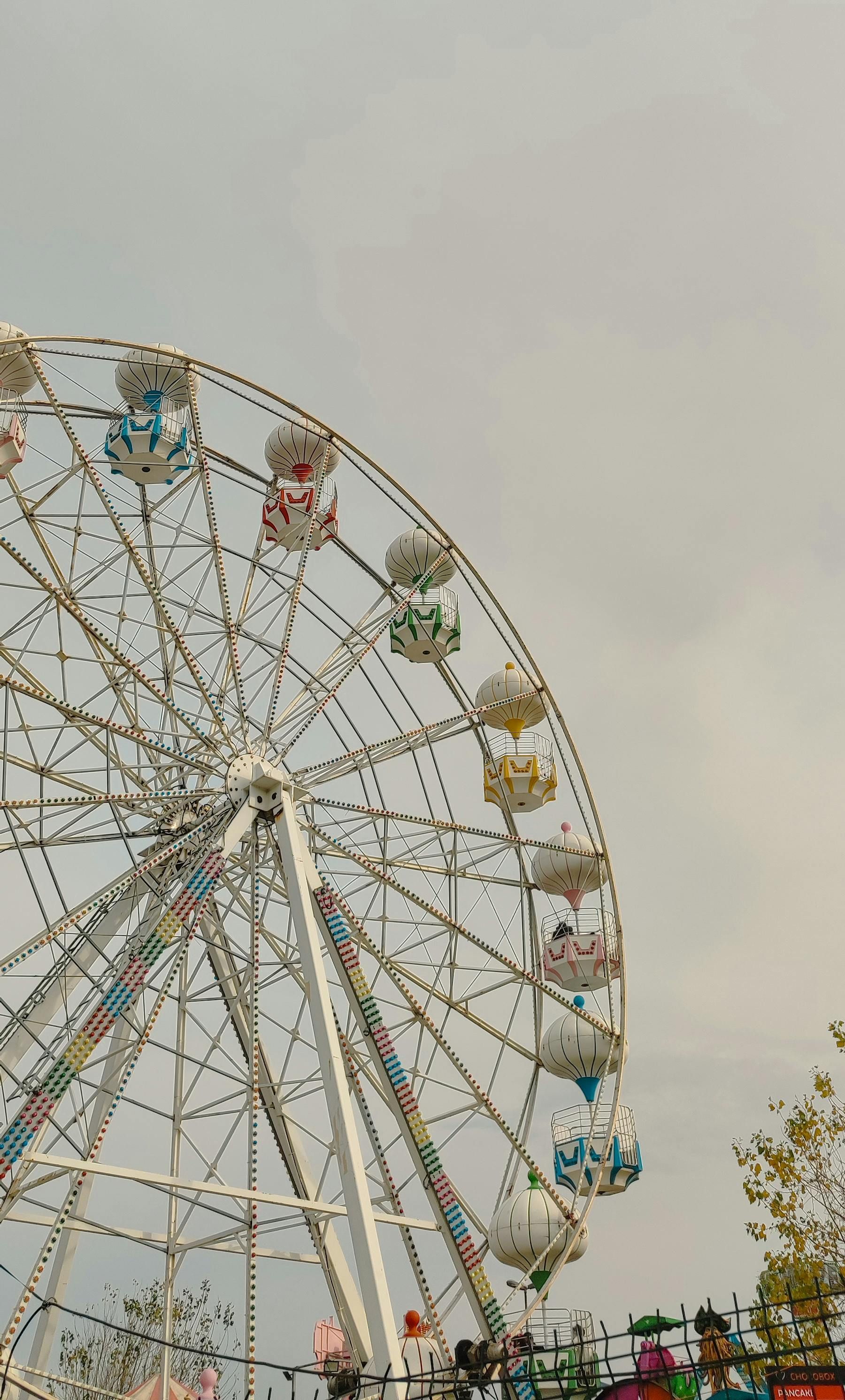 A ferris wheel at an amusement park with a cloudy sky in the background.
