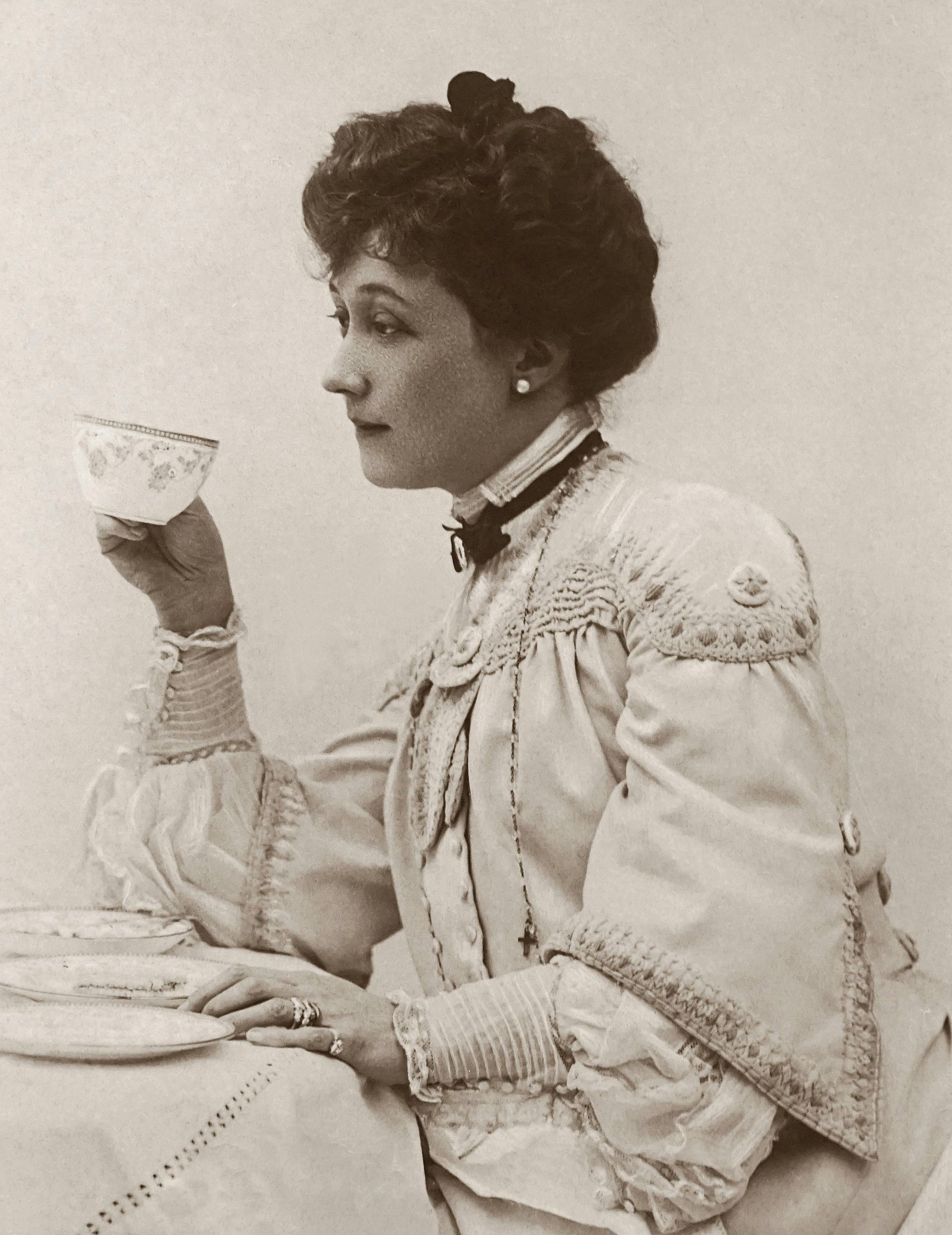 A woman in a white dress is drinking from a cup