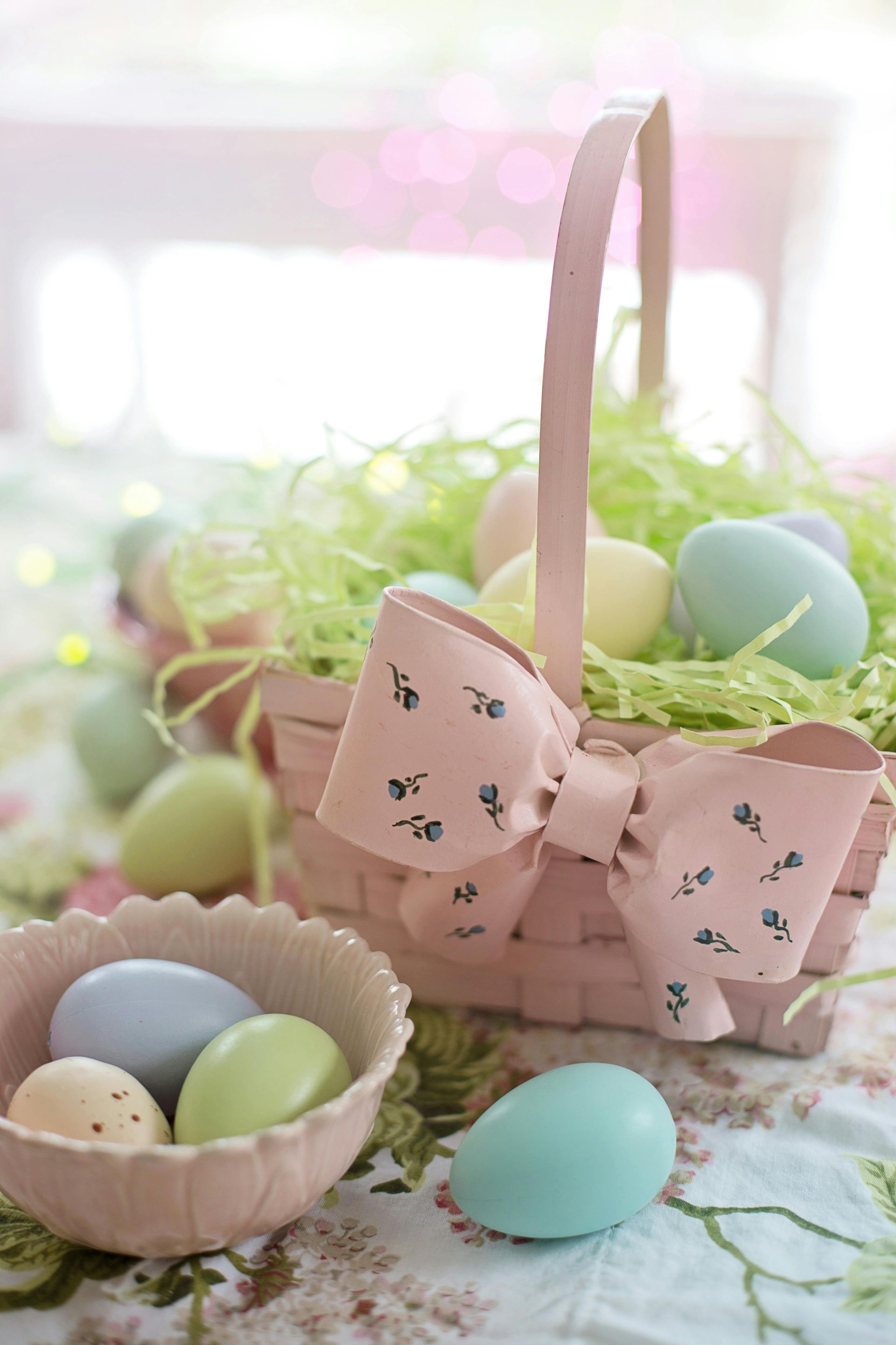 A basket filled with easter eggs and a bowl of eggs on a table.