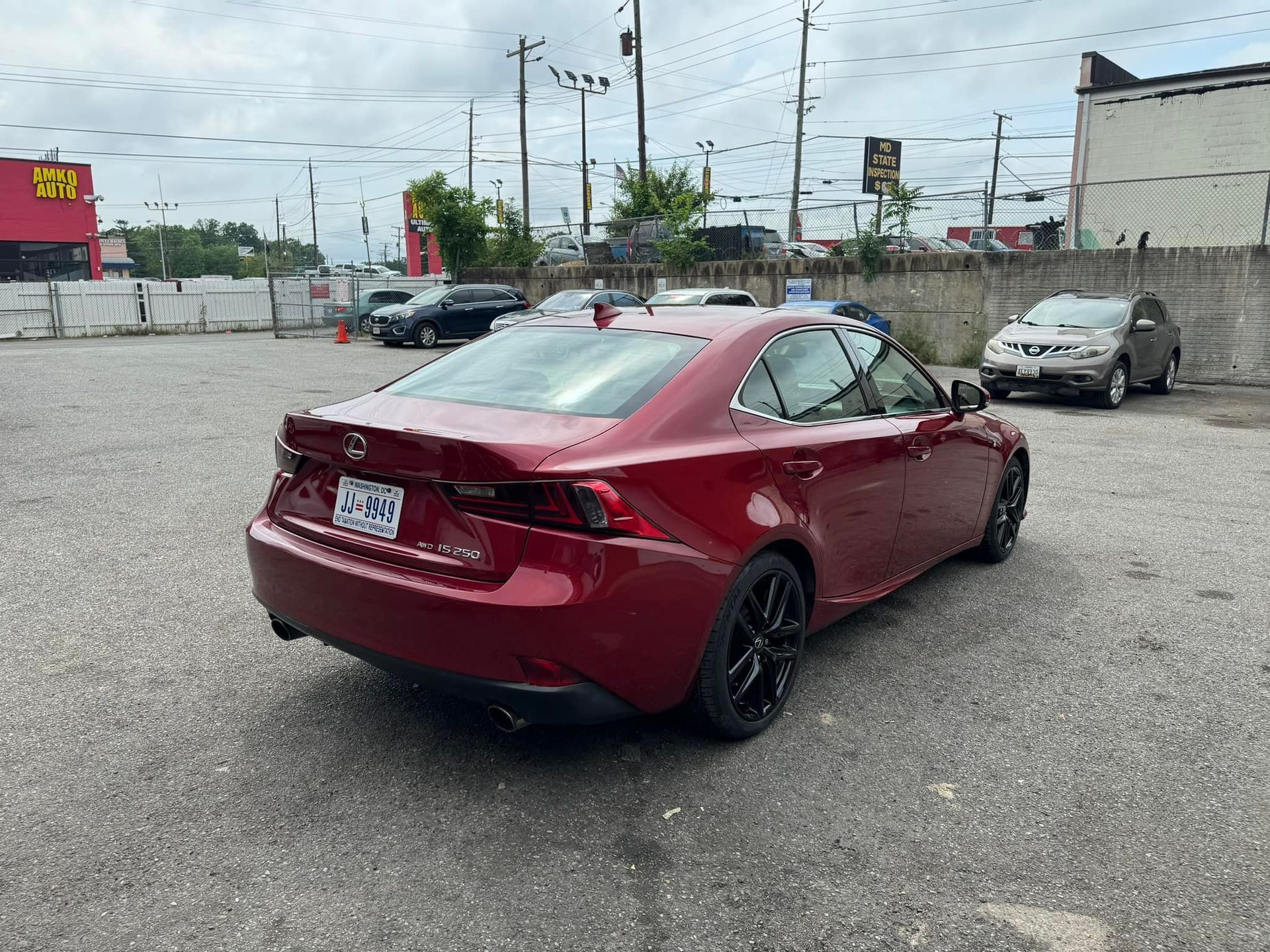 Red sedan parked in a lot, viewed from the rear-left side.