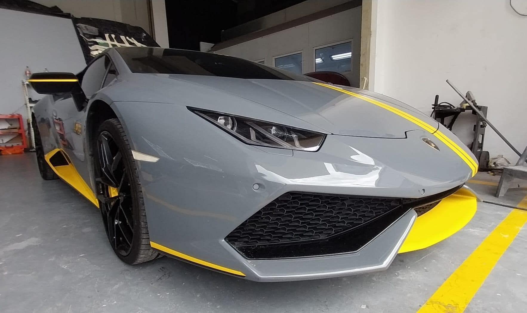 Gray sports car with yellow accents parked in a garage