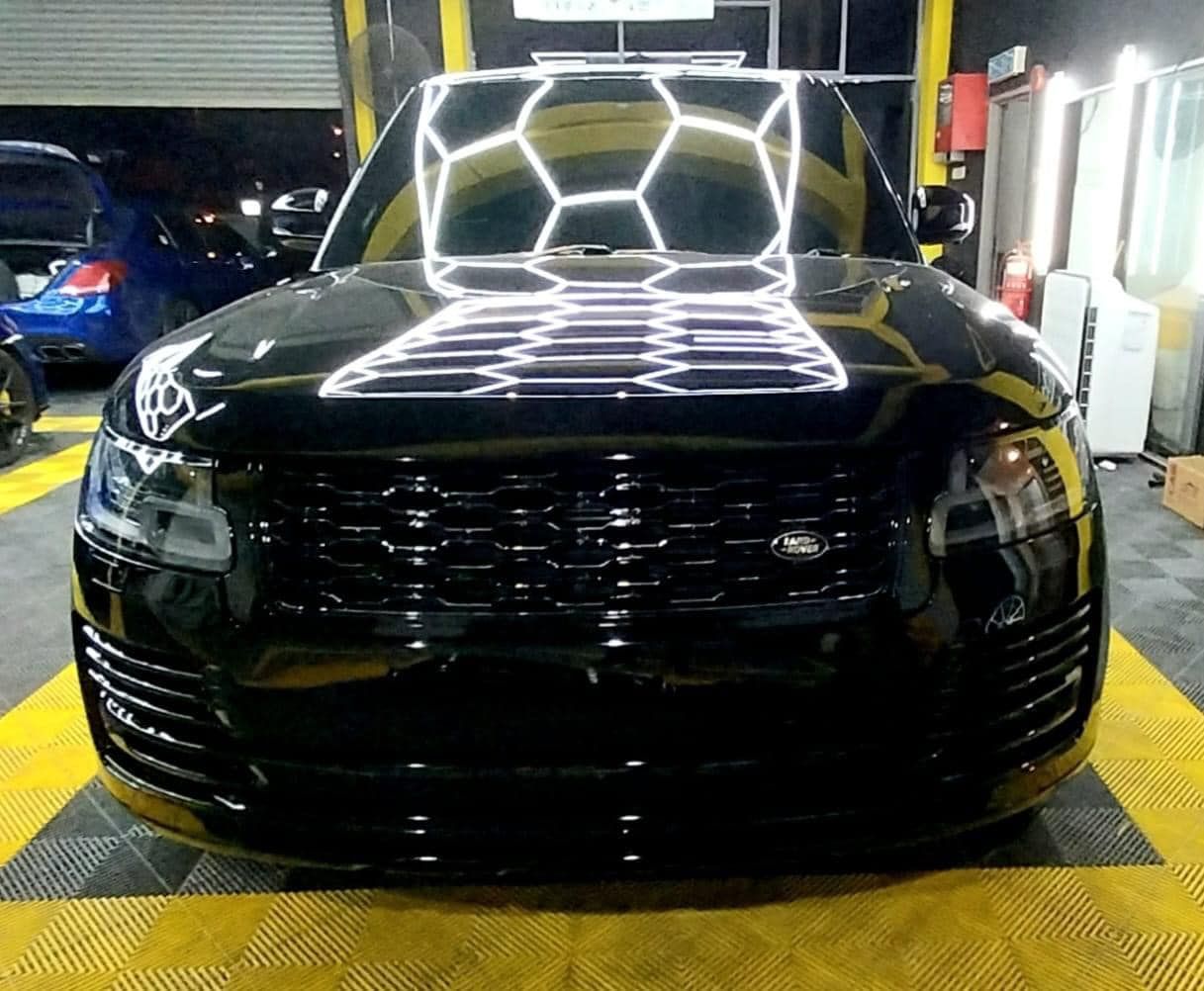 Black SUV in a garage with bright geometric light reflections on the hood and windshield
