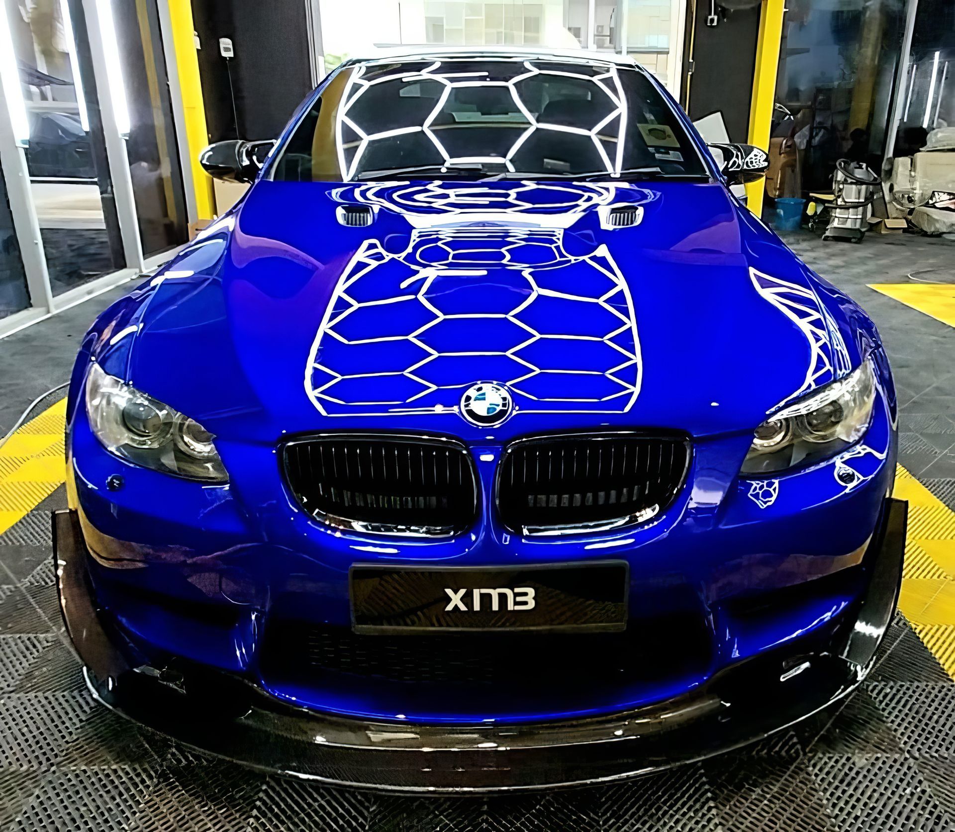Blue BMW sports car front view in a garage, with a black grille and glossy hood reflections