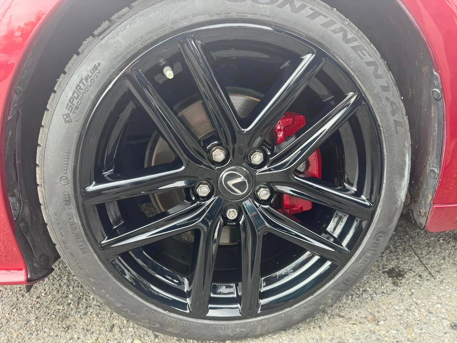 Close-up of a black alloy car wheel with red brake caliper on a red vehicle.