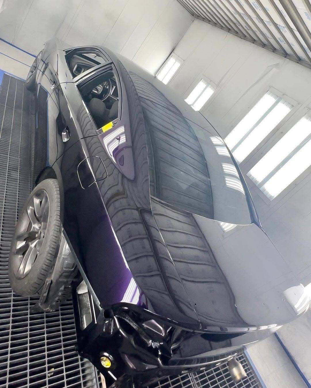 Purple sports car in a showroom on a metal platform, shown at a tilted angle from above.