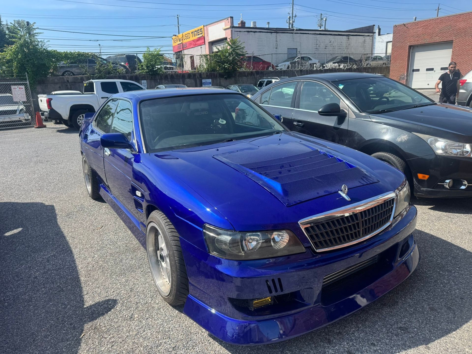 Blue sports coupe parked in a lot beside a black car on a sunny day