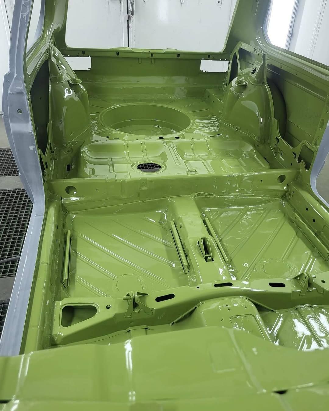 Green-painted car interior body shell with exposed metal floor and seats removed