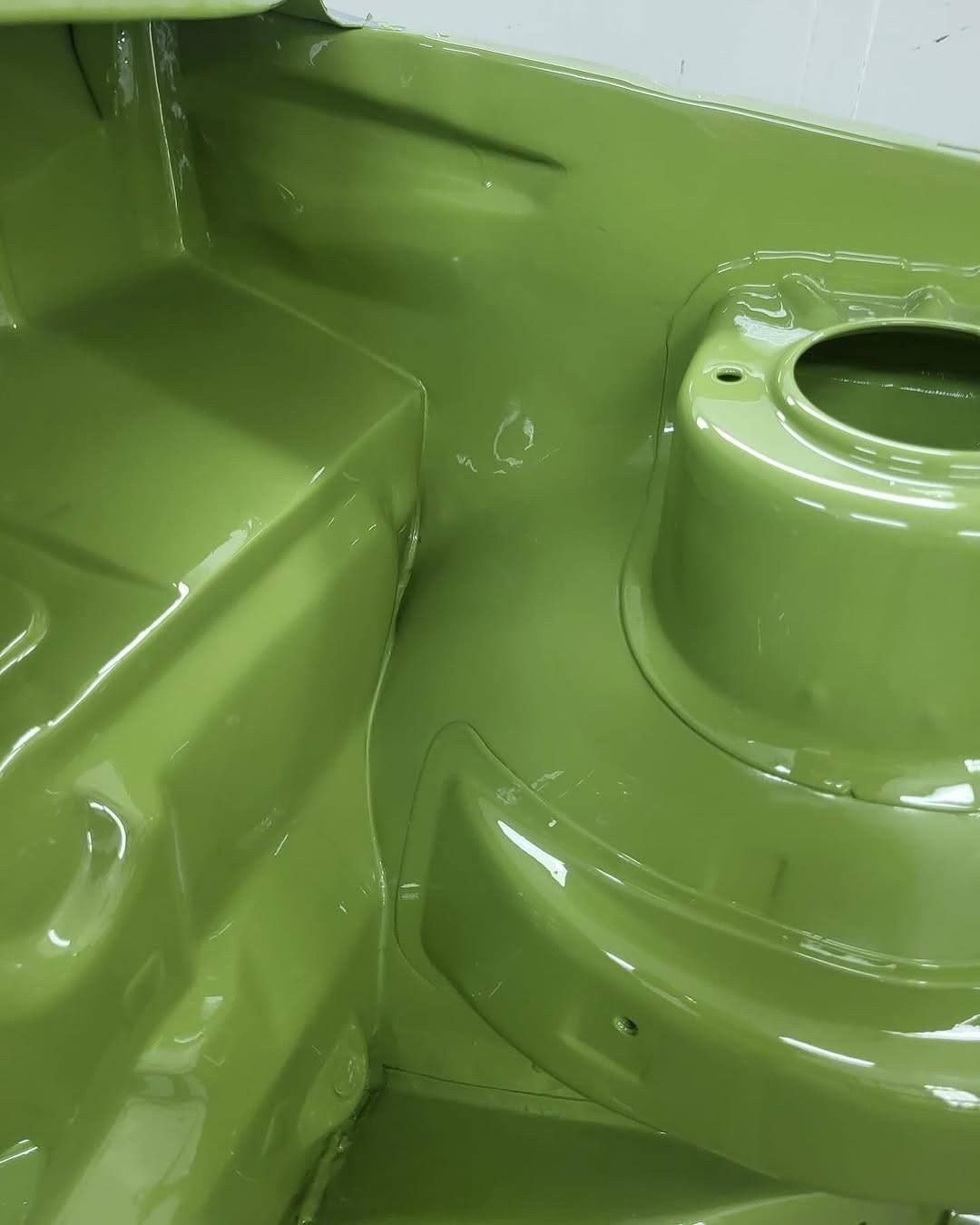 Close-up of glossy lime-green painted metal machinery components with bolts and circular opening.