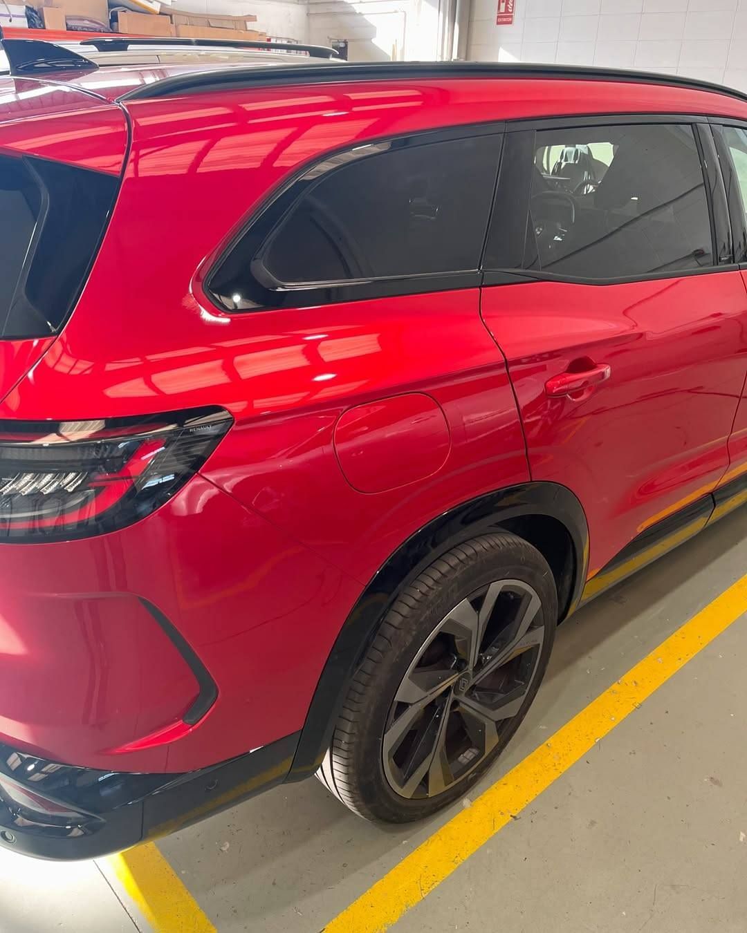 Red SUV parked in an indoor garage, viewed from the rear side.