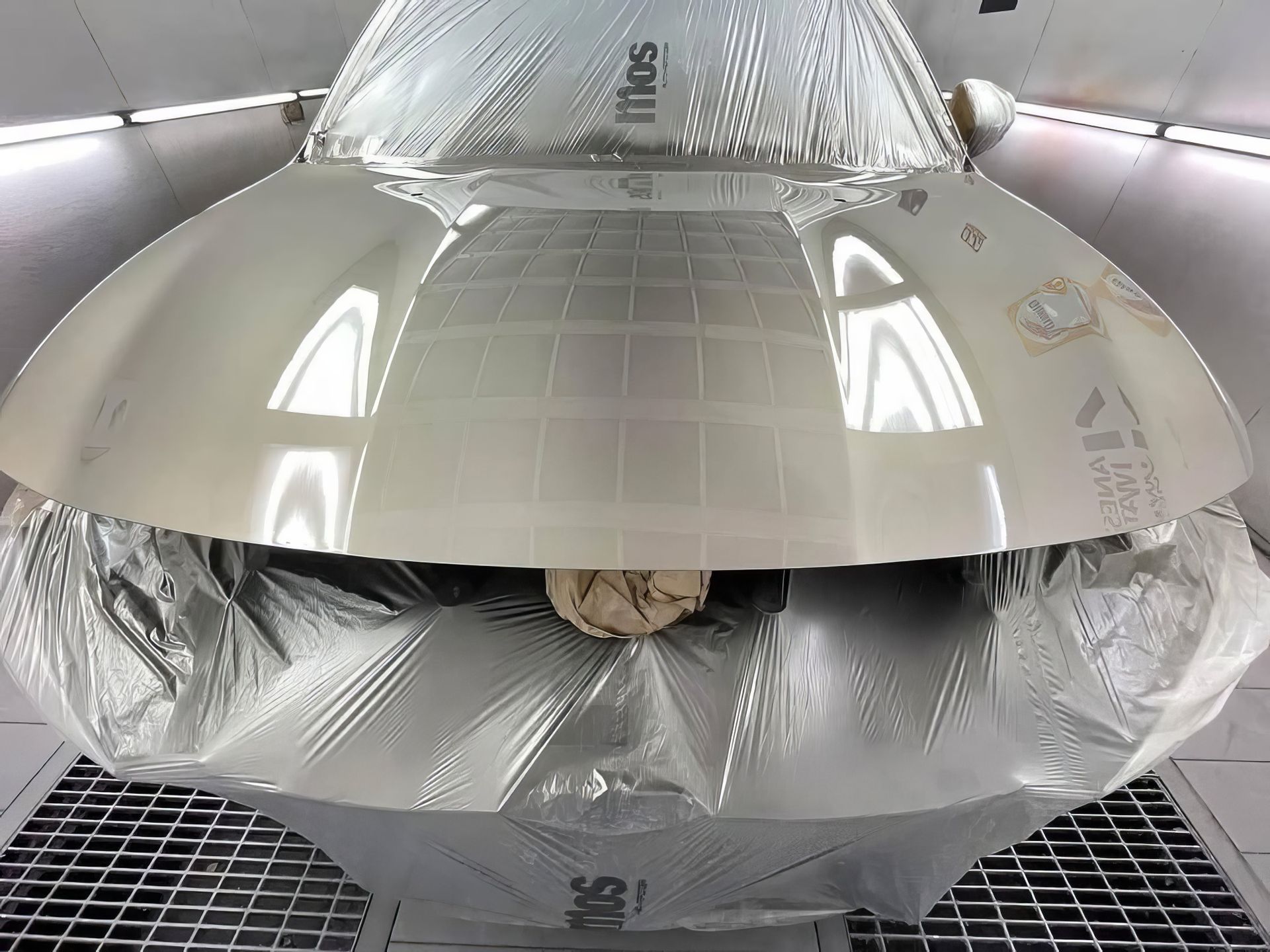 Large metallic industrial dome-like object with reflective silver surfaces in a workshop booth
