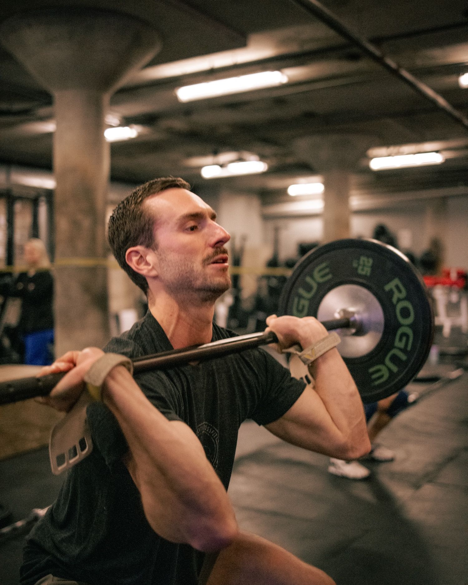 Man at Derby City Fitness gym in Louisville, KY lifting barbell overhead, focused expression