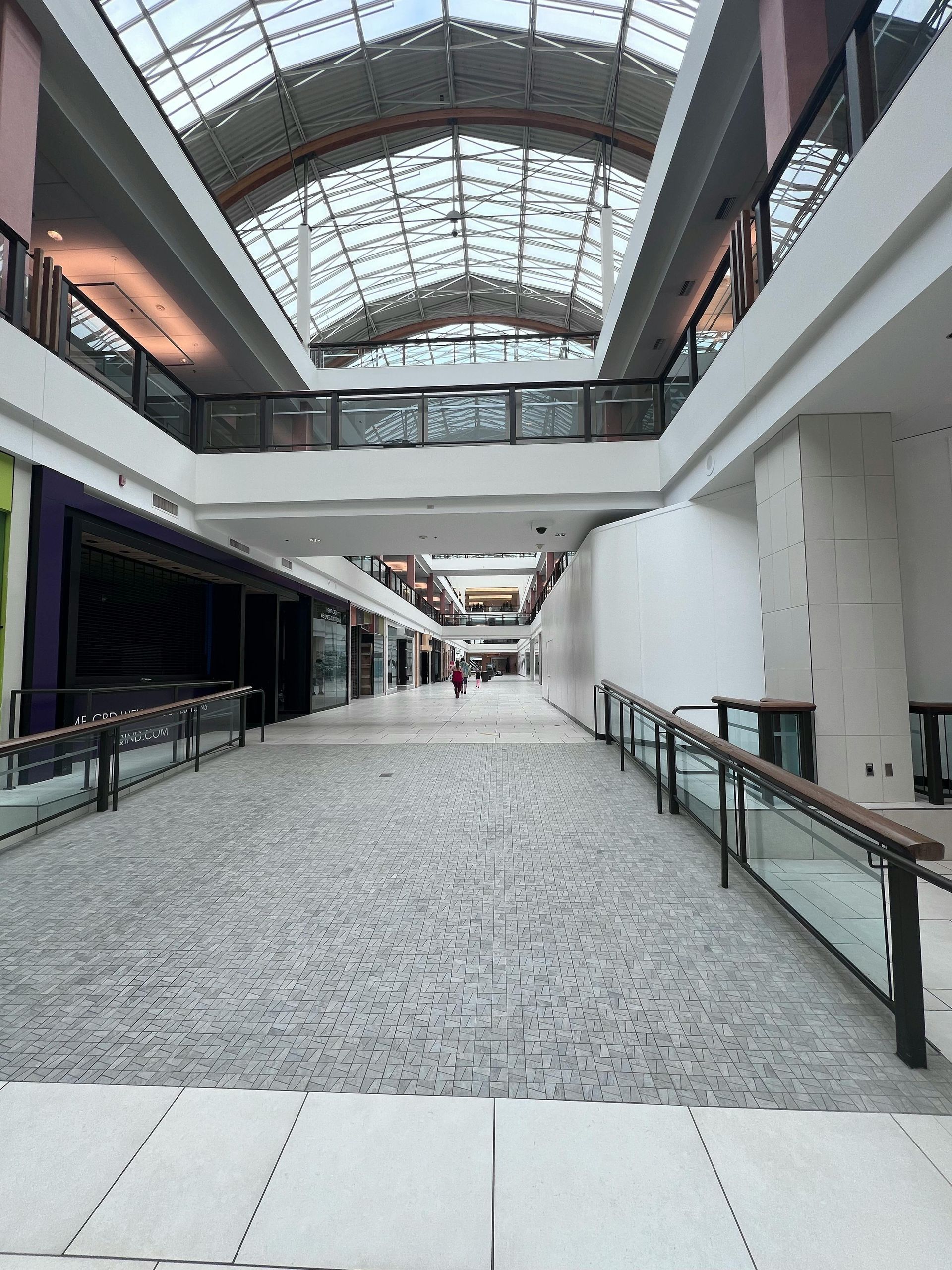Empty shopping mall interior with skylight and two levels.