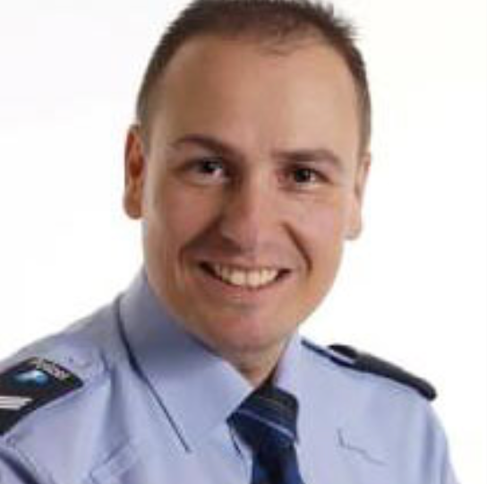 Ein Mann in blauem Hemd und Krawatte lächelt in die Kamera.