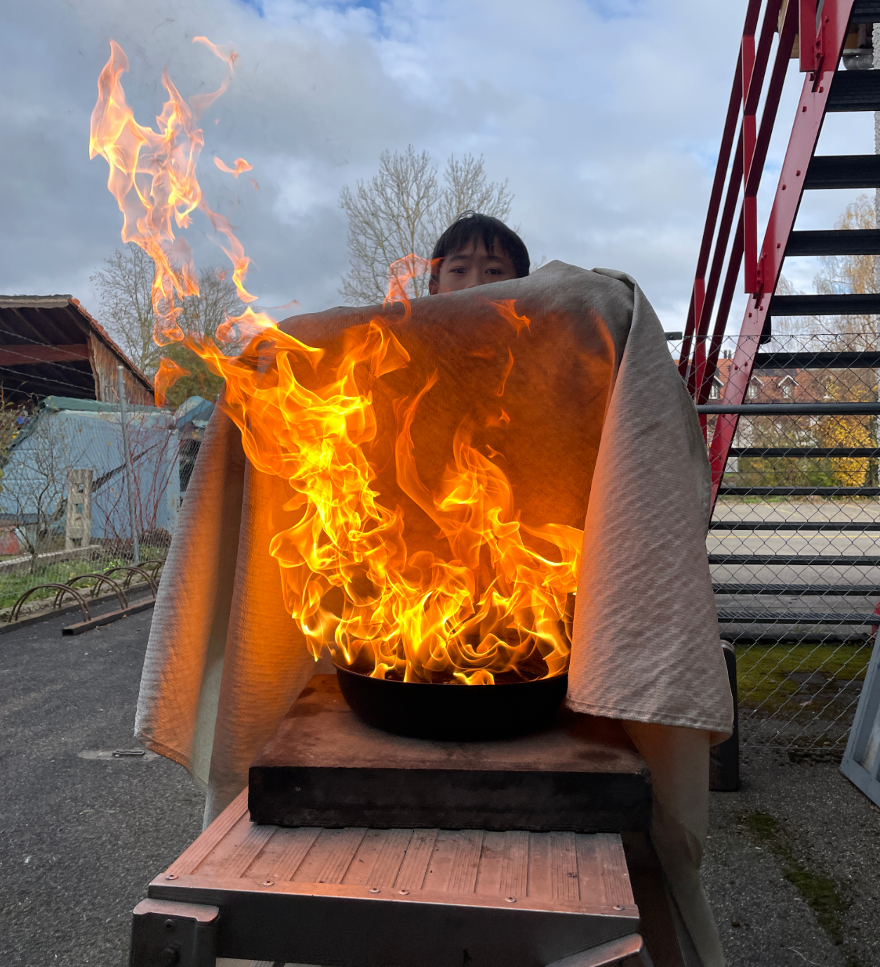 Eine Person hält eine Pfanne mit Feuer auf einem Holztisch