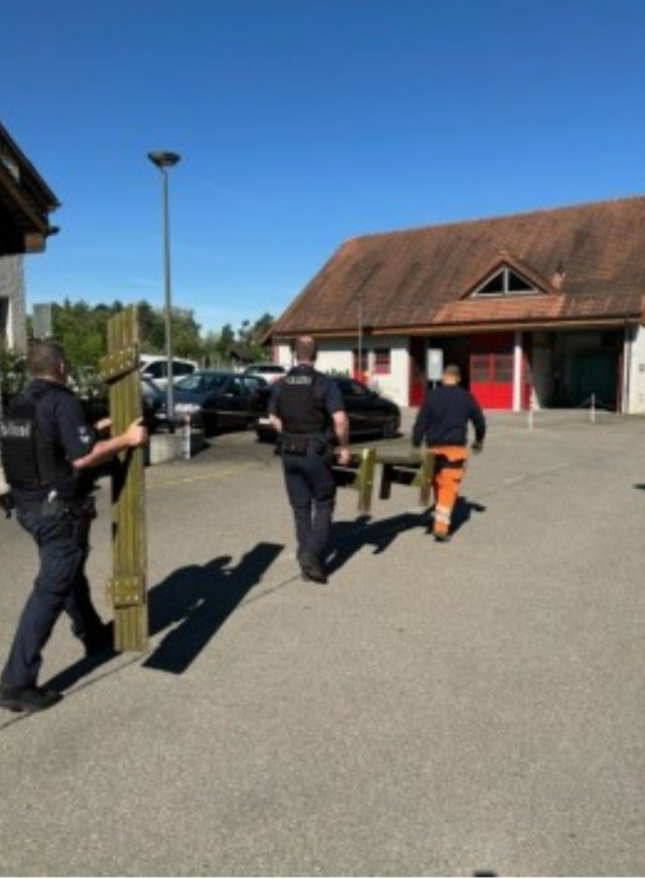 Eine Gruppe von Männern, die eine Holzstange auf einem Parkplatz tragen