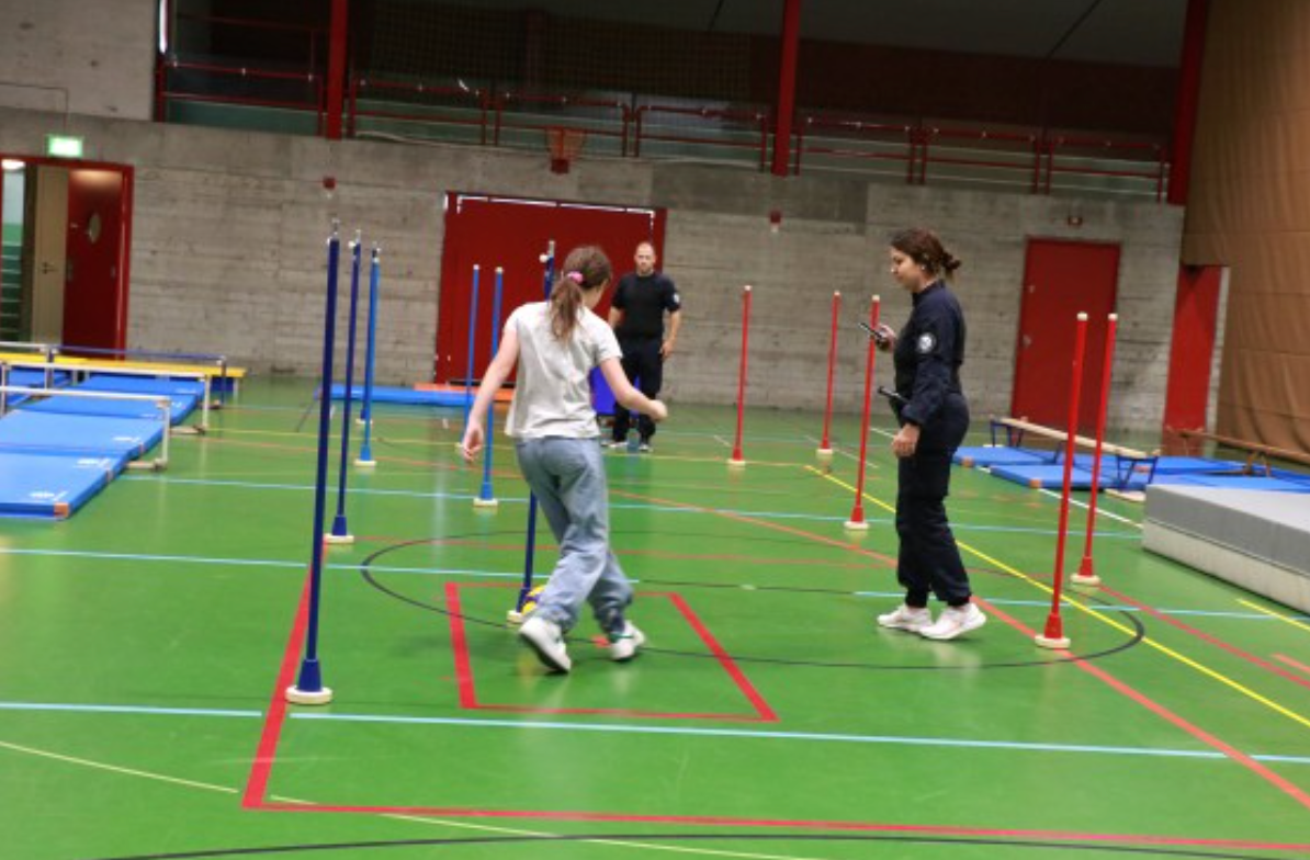 Eine Gruppe von Leuten spielt in einer Turnhalle ein Spiel.