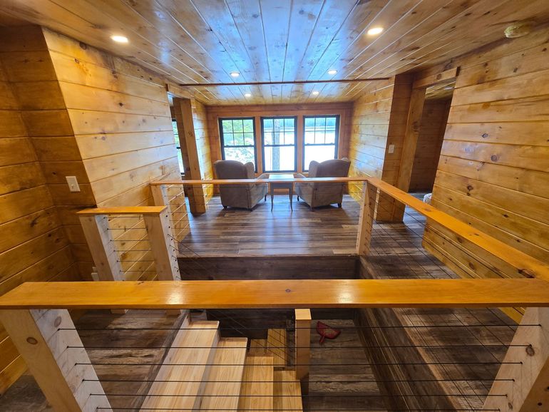 An interior view of a room under construction, featuring exposed ceiling rafters with insulation and a concrete floor.