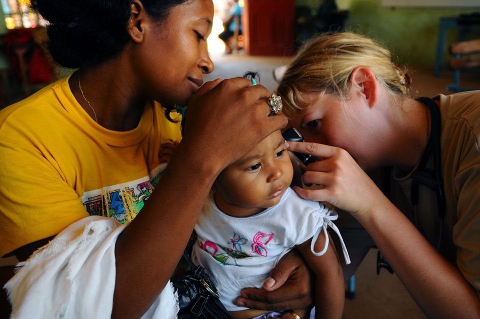 woman checking baby girl's ear