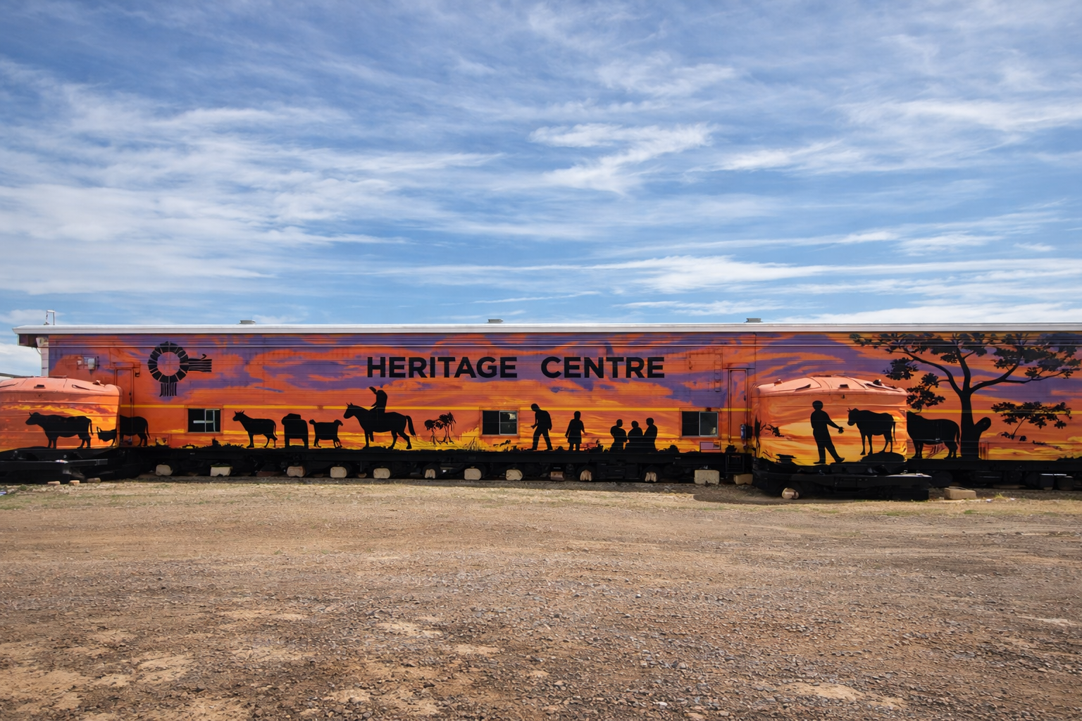 Heritage Centre building mural in an open, dry landscape under a blue sky