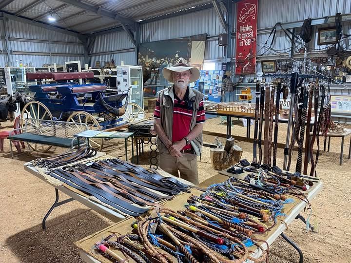 Person standing by tables of handmade leather goods in a rustic market stall