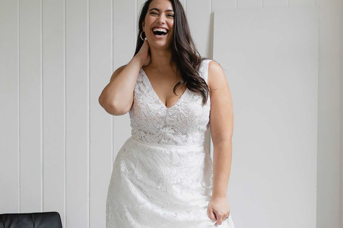 Woman putting on earrings in front of a mirror, preparing for an event.
