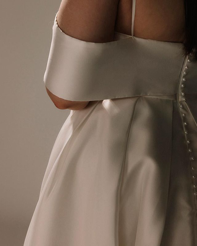White satin wedding dress bodice with off-the-shoulder sleeve detail and beaded back.