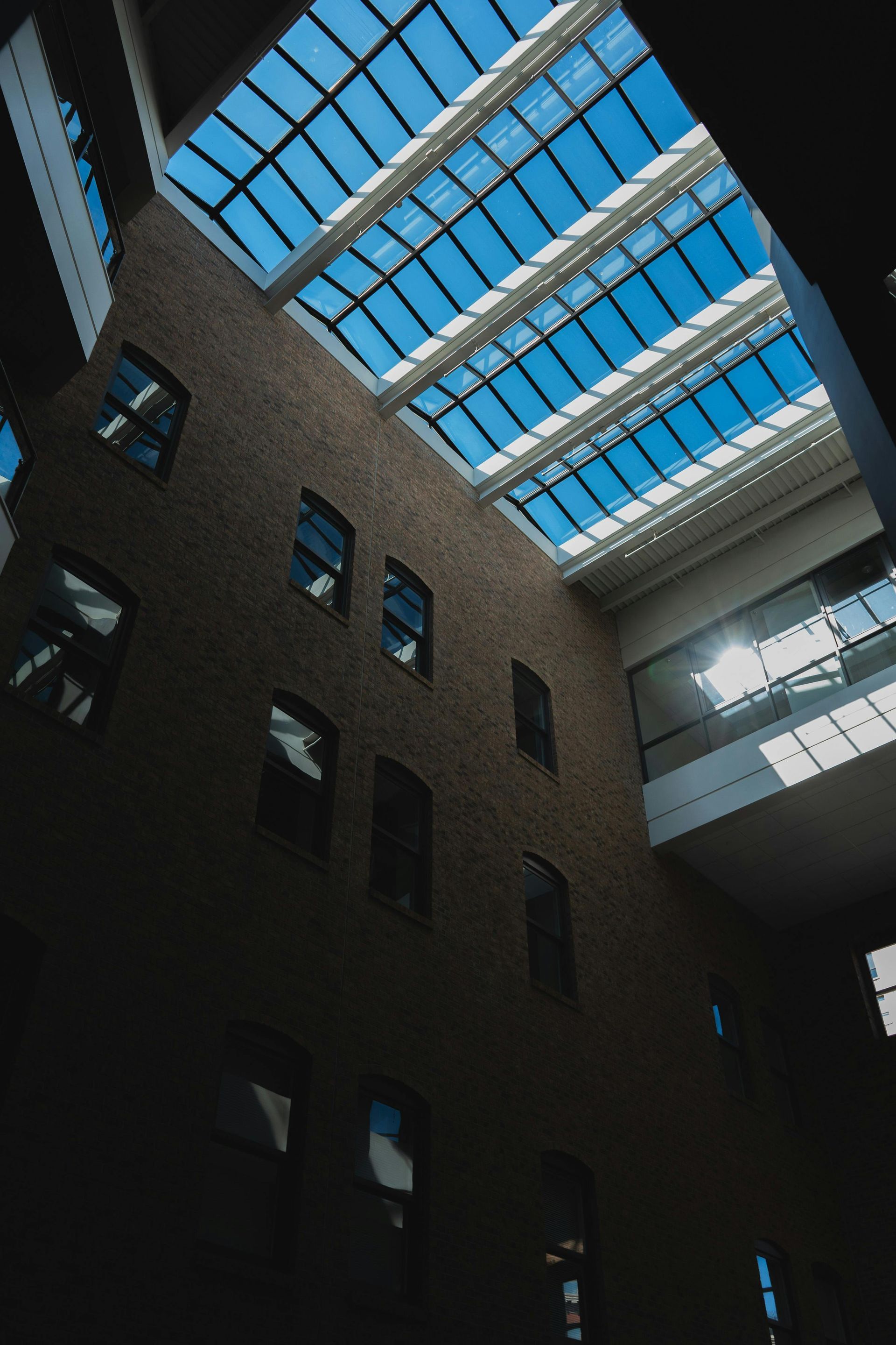 Brick building interior with glass skylight and windows, bathed in sunlight.
