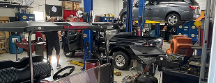 A man is working on a golf cart in a garage. | Ed's Automotive