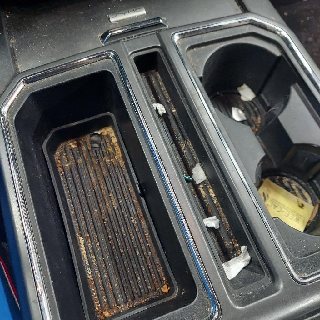 A dirty center console in a car with two cup holders | Ed's Automotive