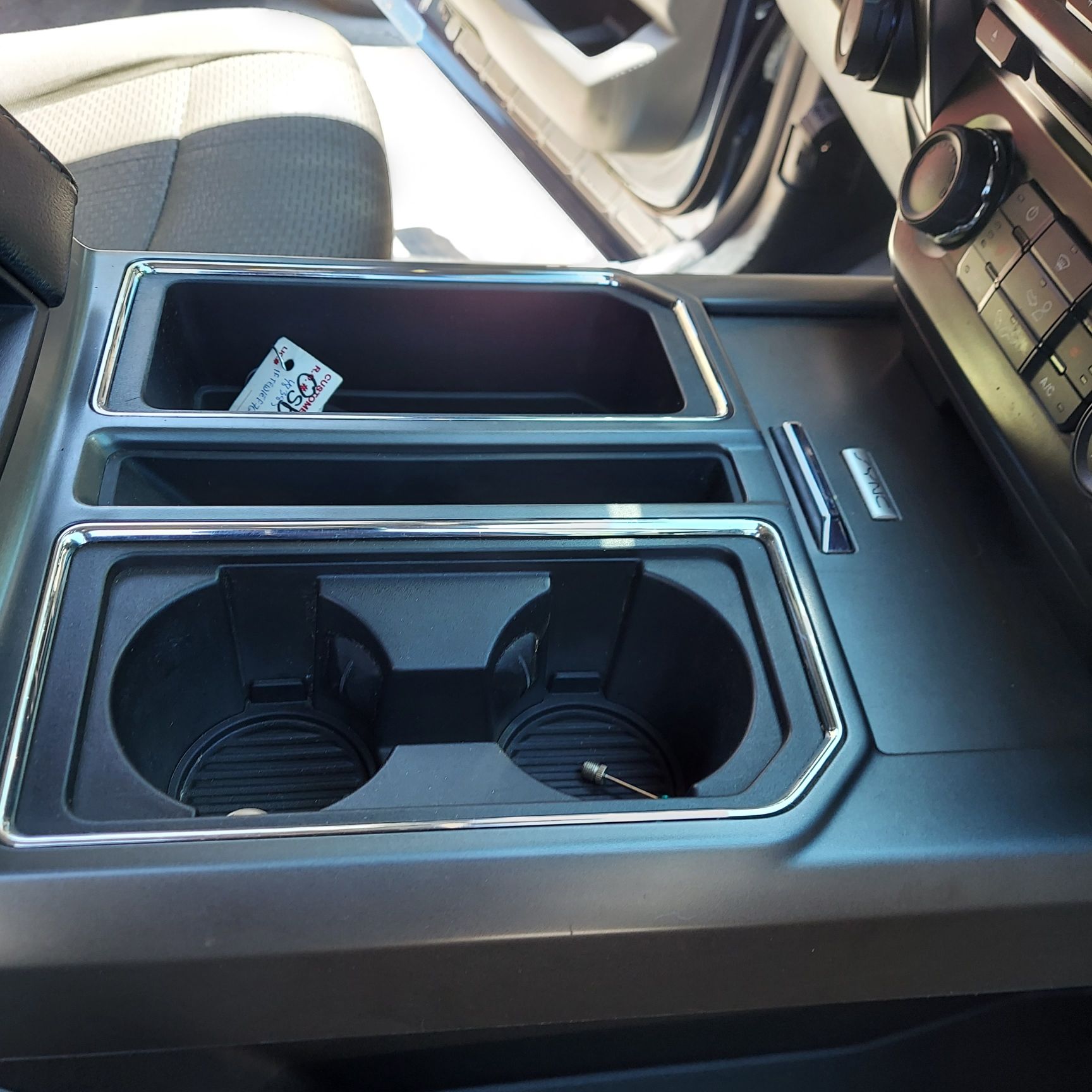 A car console with two cup holders and a remote control | Ed's Automotive