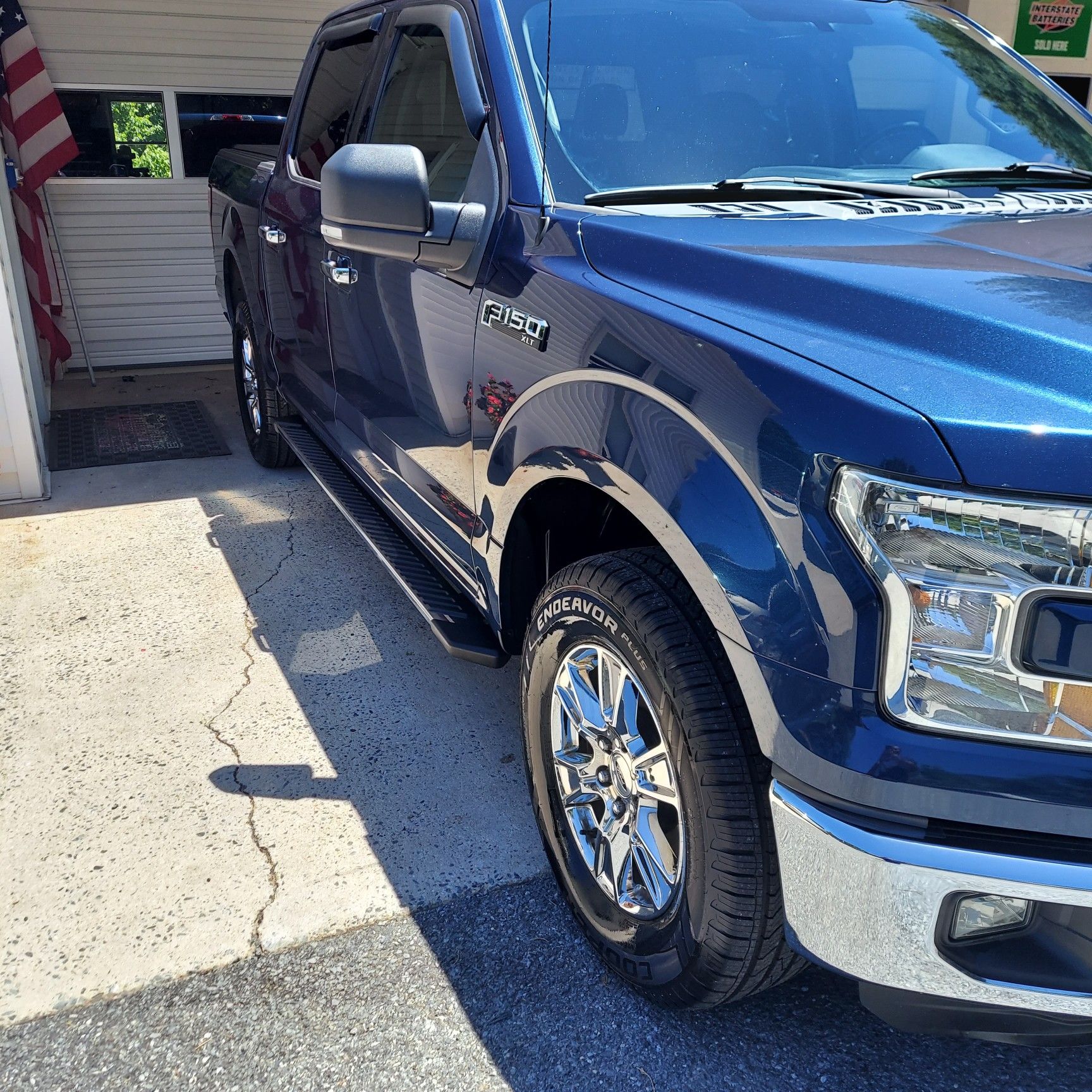 A blue ford truck is parked in front of a garage | Ed's Automotive