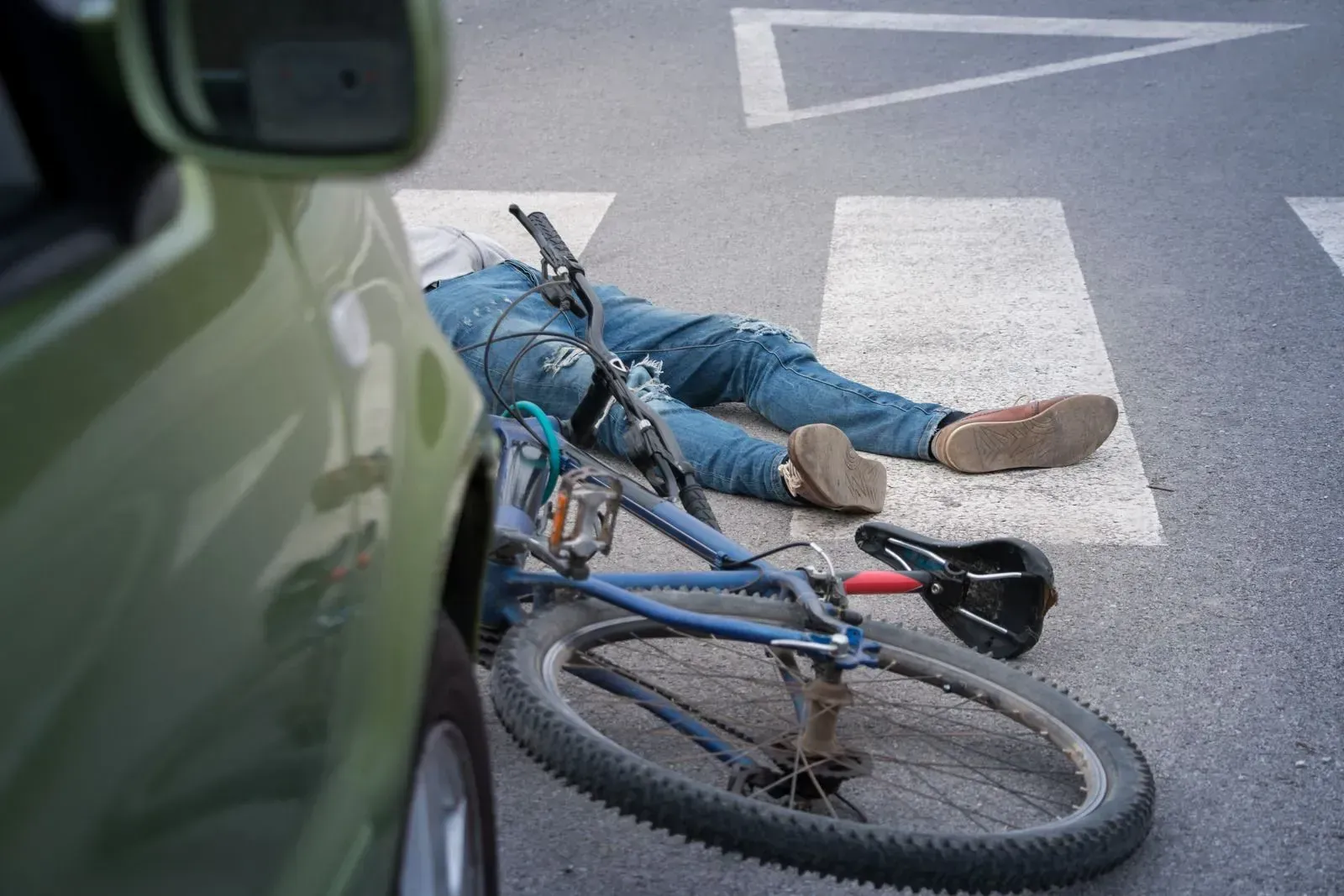 A man is laying on the ground next to a bicycle.