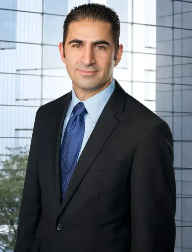 A man in a suit and tie is standing in front of a window.